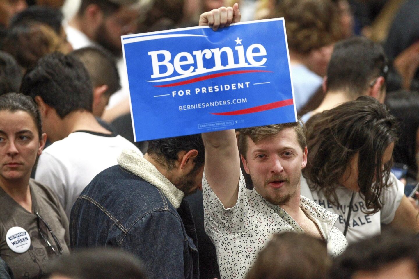 A Bernie Sanders supporter holds a sign as he and other supporters wait for Democratic presidential candidate Bernie Sanders.