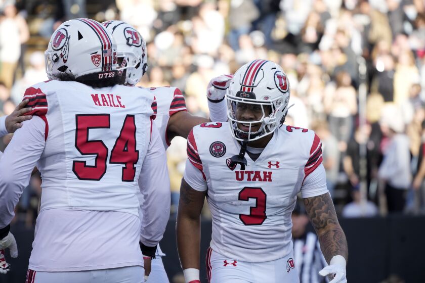 Utah quarterback Ja'Quinden Jackson, right, is congratulated by offensive lineman Paul Maile after running for a touchdown in the first half of an NCAA college football game against Colorado, Saturday, Nov. 26, 2022, in Boulder, Colo. (AP Photo/David Zalubowski)