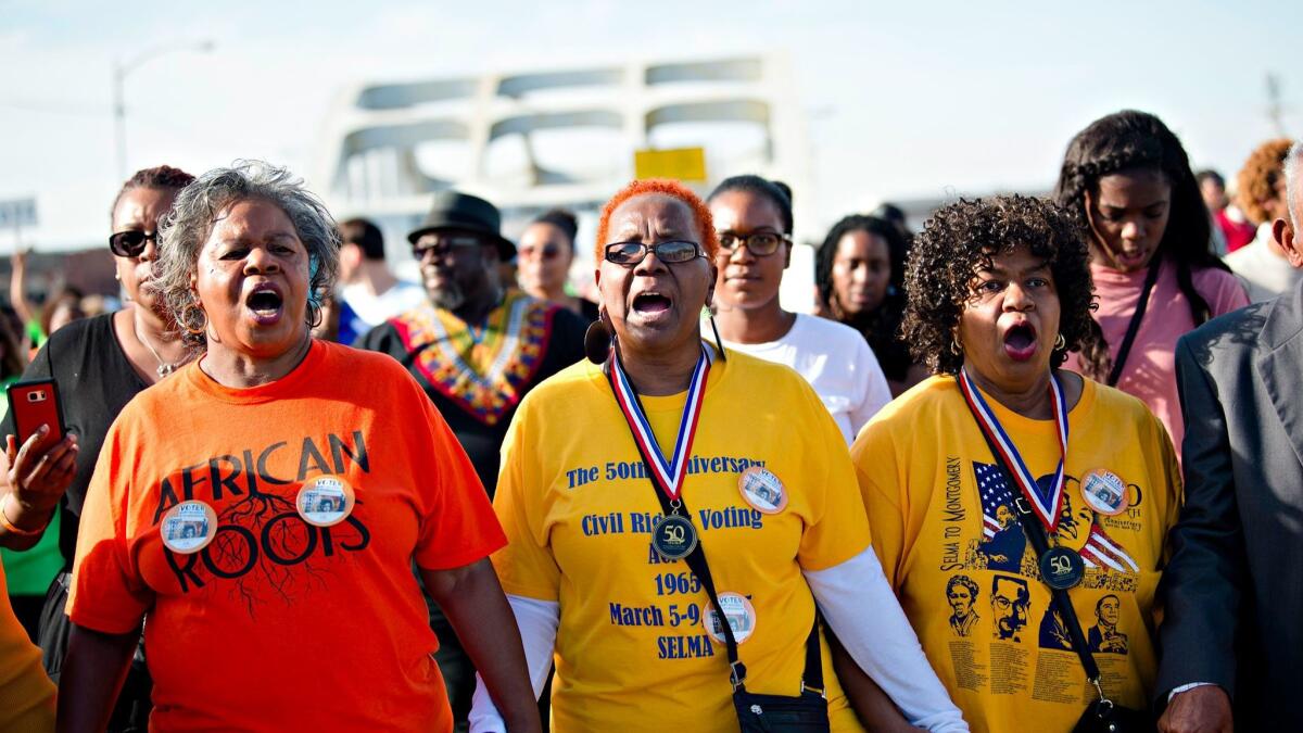 Marcia McMilan Edwards, left, Helen Brooks and Ruth Anthony lead the march across the Edmund Pettus Bridge on Sunday in Selma, Ala.