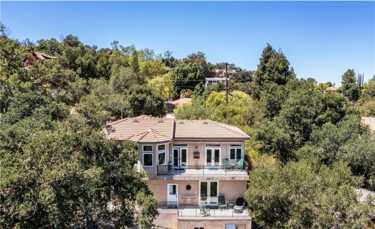 A multilevel home with patios. It is surrounded by trees.