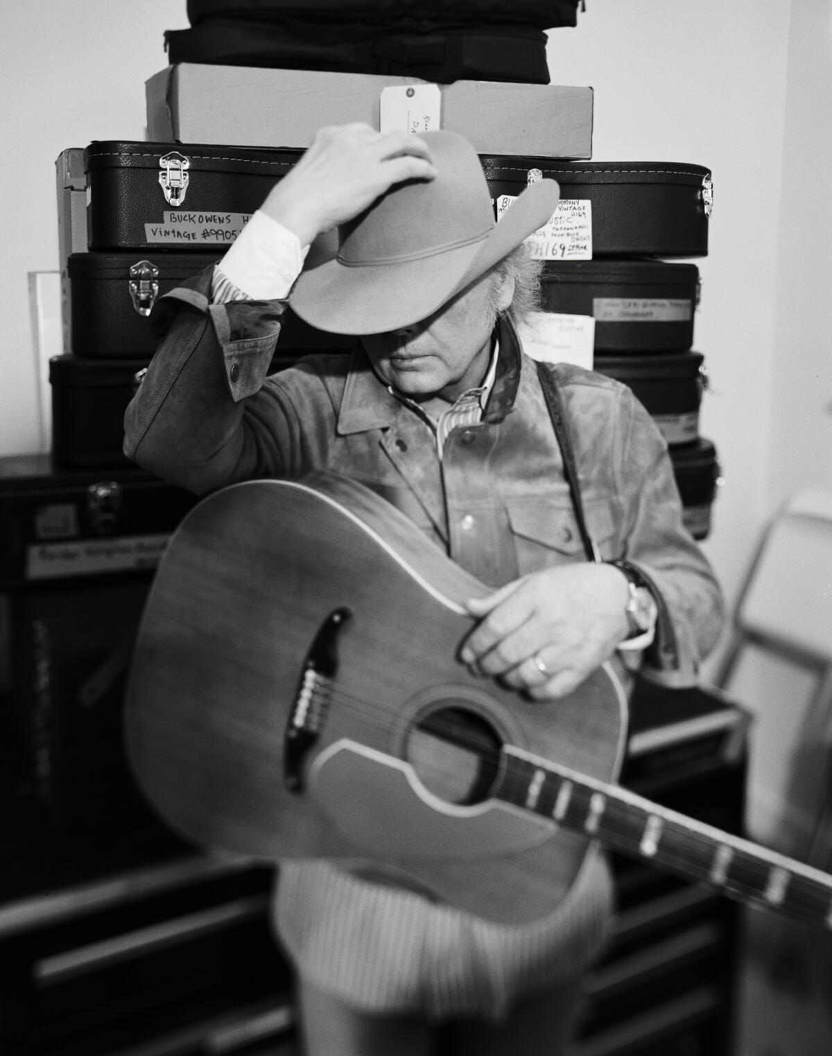 A guitar-wearing Dwight Yoakam tips his cowboy hat low.