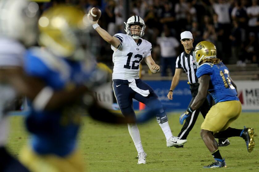BYU quarterback Tanner Mangum is pressured into throwing an interception in the closing moments of a 24-23 loss to UCLA on Saturday at the Rose Bowl.