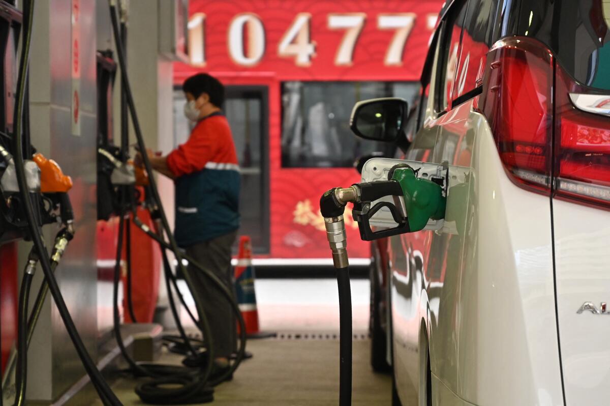 Petrol station attendants fill up vehicles at a petrol station in Hong Kong on March 7, 2022 with fuel prices rising.