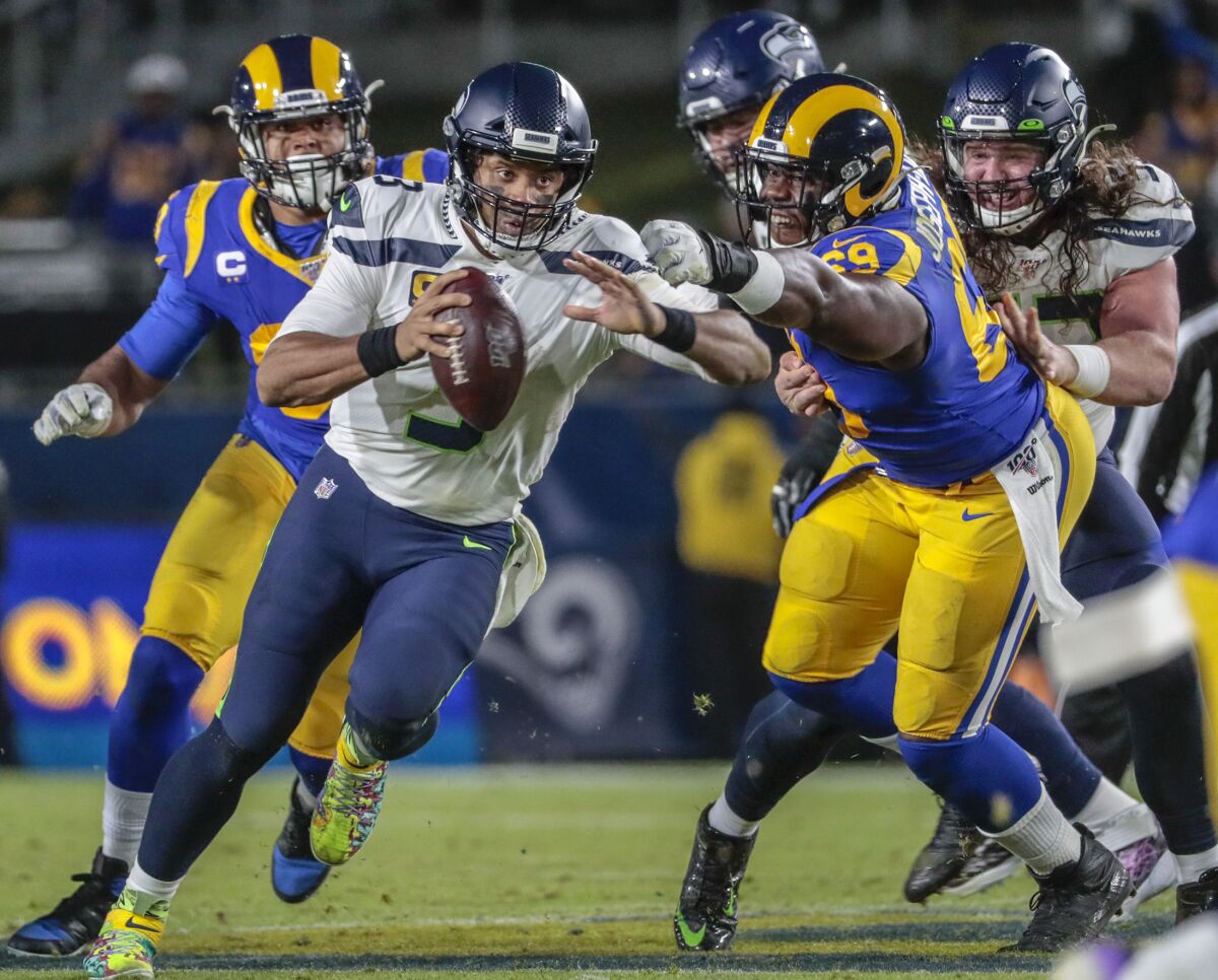 Seattle Seahawks quarterback Russell Wilson (3) scrambles past the Rams' pass rush in December 2019.