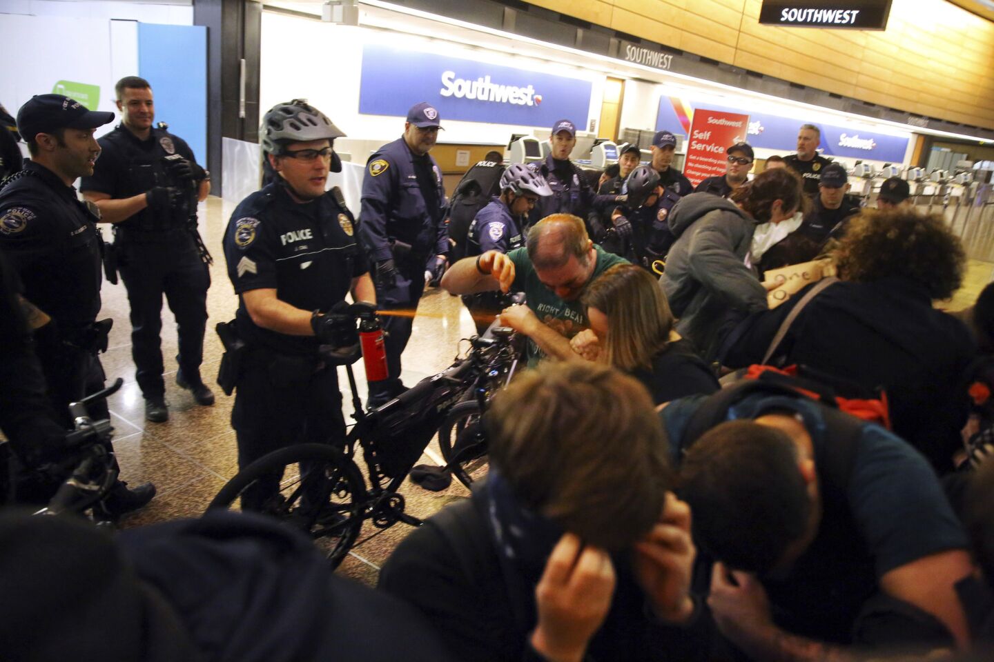 Seattle police use pepper spray and push the last group of protesters out of a Seattle-Tacoma International Airport terminal after giving a final dispersal order at about 2 a.m Sunday.