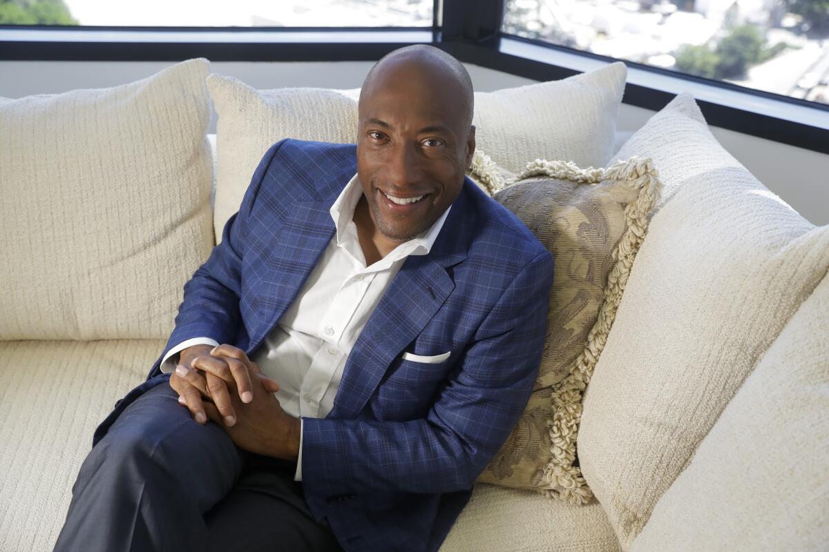 Byron Allen sits on a couch.
