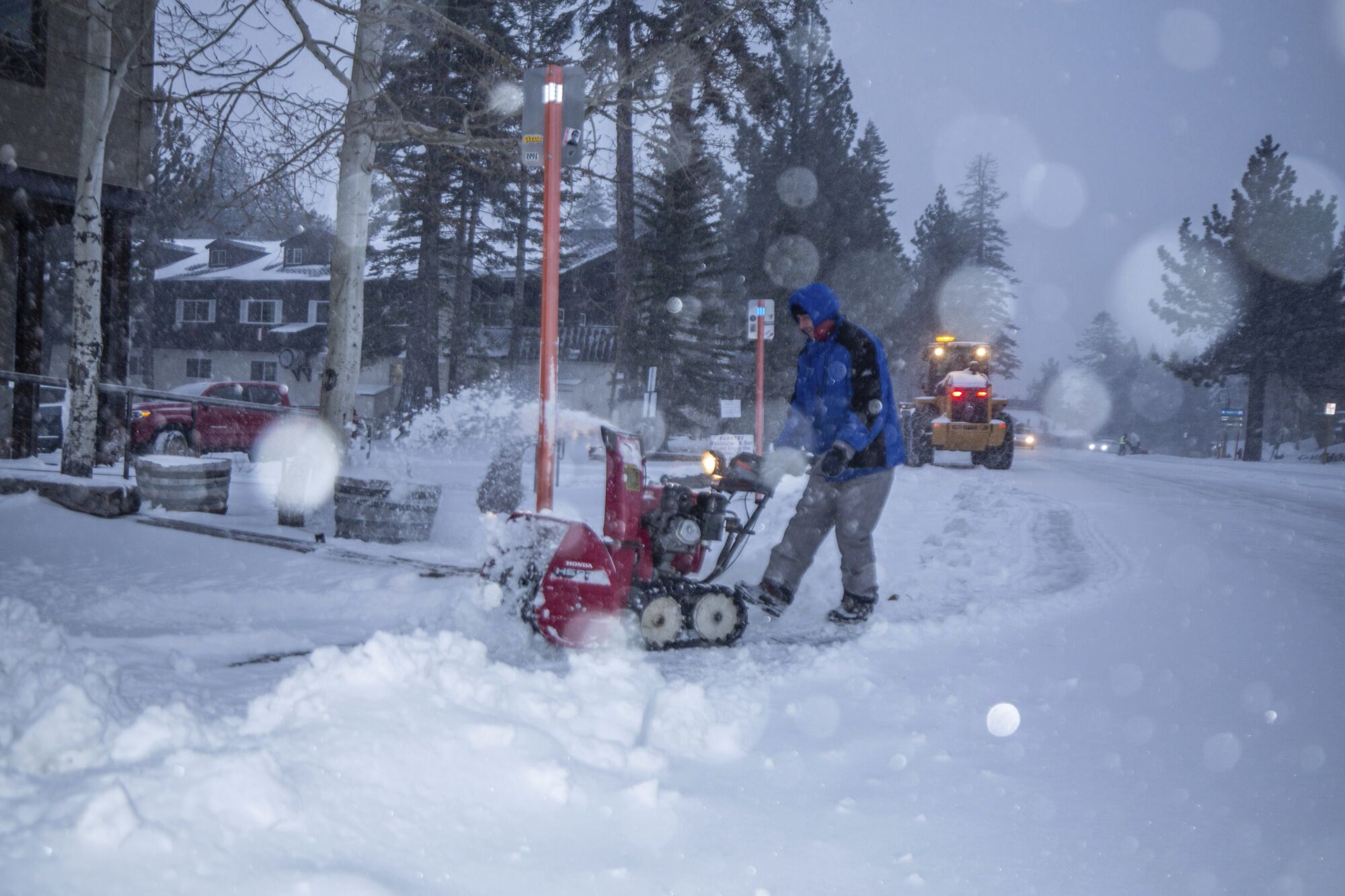 A man uses a snow blower to clear a street in Mammoth Lakes