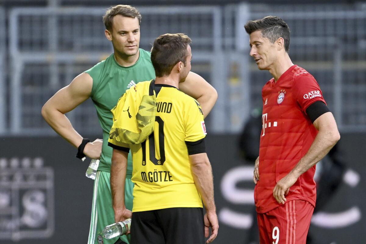 Munich's Manuel Neuer, left, and Robert Lewandowski, right, talk to Dortmund's Mario Goetze, center, after the German Bundesliga soccer match between Borussia Dortmund and FC Bayern Munich in Dortmund, Germany, Tuesday, May 26, 2020. The German Bundesliga is the world's first major soccer league to resume after a two-month suspension because of the coronavirus pandemic. (Federico Gambarini/DPA via AP, Pool)