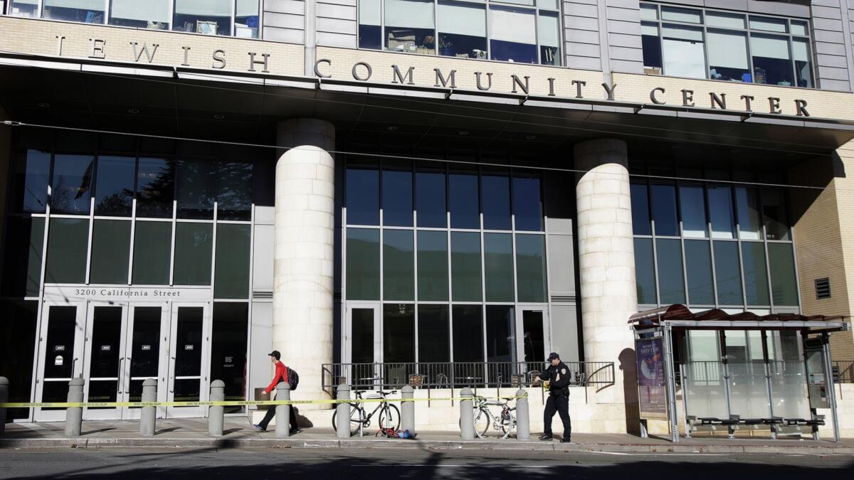 A police officer removes police tape along California Street in San Francisco on Thursday. Authorities say bomb threats sent to locations across the U.S. appear to be hoaxes.