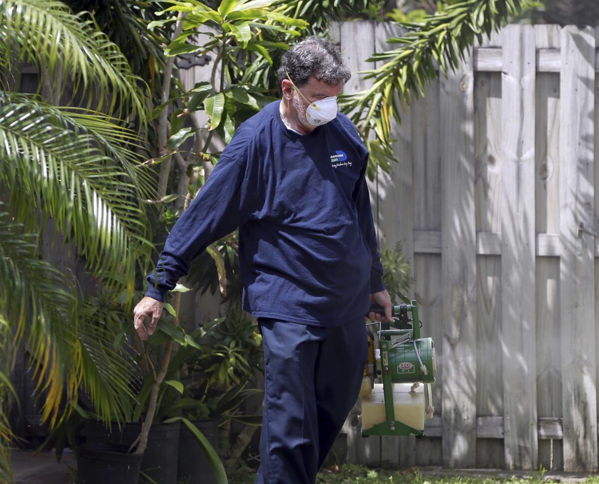 Un inspector de la unidad de control de mosquitos del condado Miami-Dade, en Florida, rocía pesticida en el jardín de una casa en Miami, en ese estado. (AP Foto/Lynne Sladky)