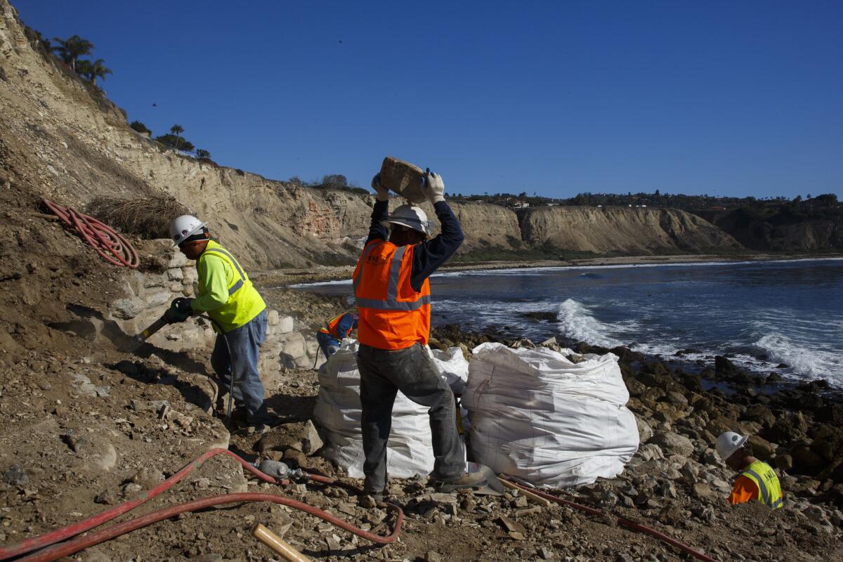 City contractors use jackhammers and muscle power to demolish a shelter built by local surfers on the shore of Lunada Bay in Palos Verdes Estates.