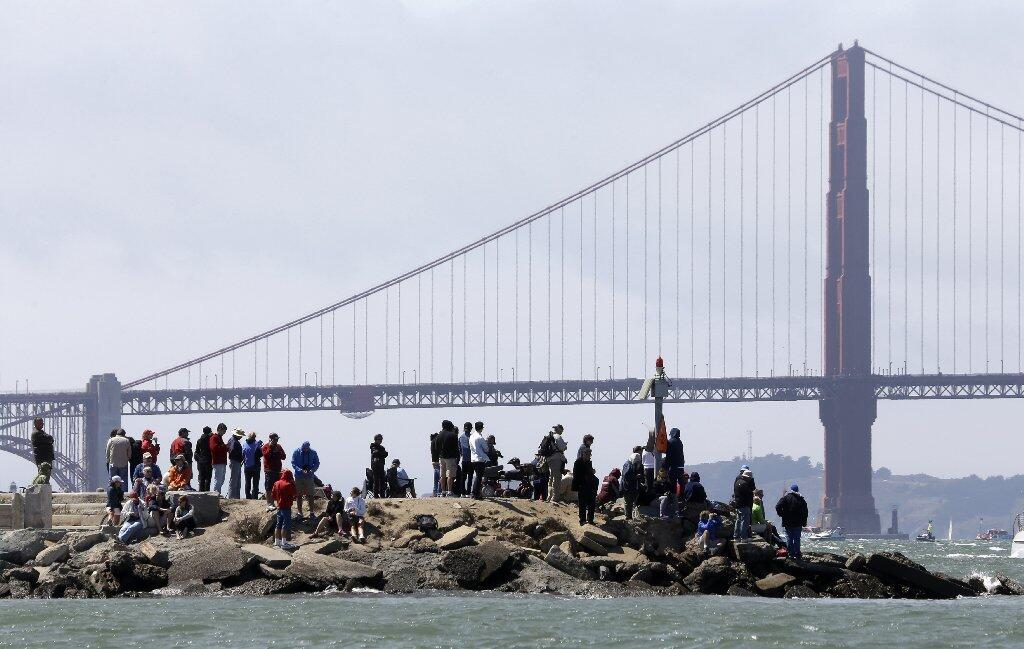 With the Golden Gate Bridge visible in the distance, spectators wait along the waterfront for the start of the eighth race between Emirates Team New Zealand and Luna Rossa Challenge, of Italy, in their America's Cup challenger series final sailing event on Saturday. The eighth race was postponed until Sunday, however, because of high wind.