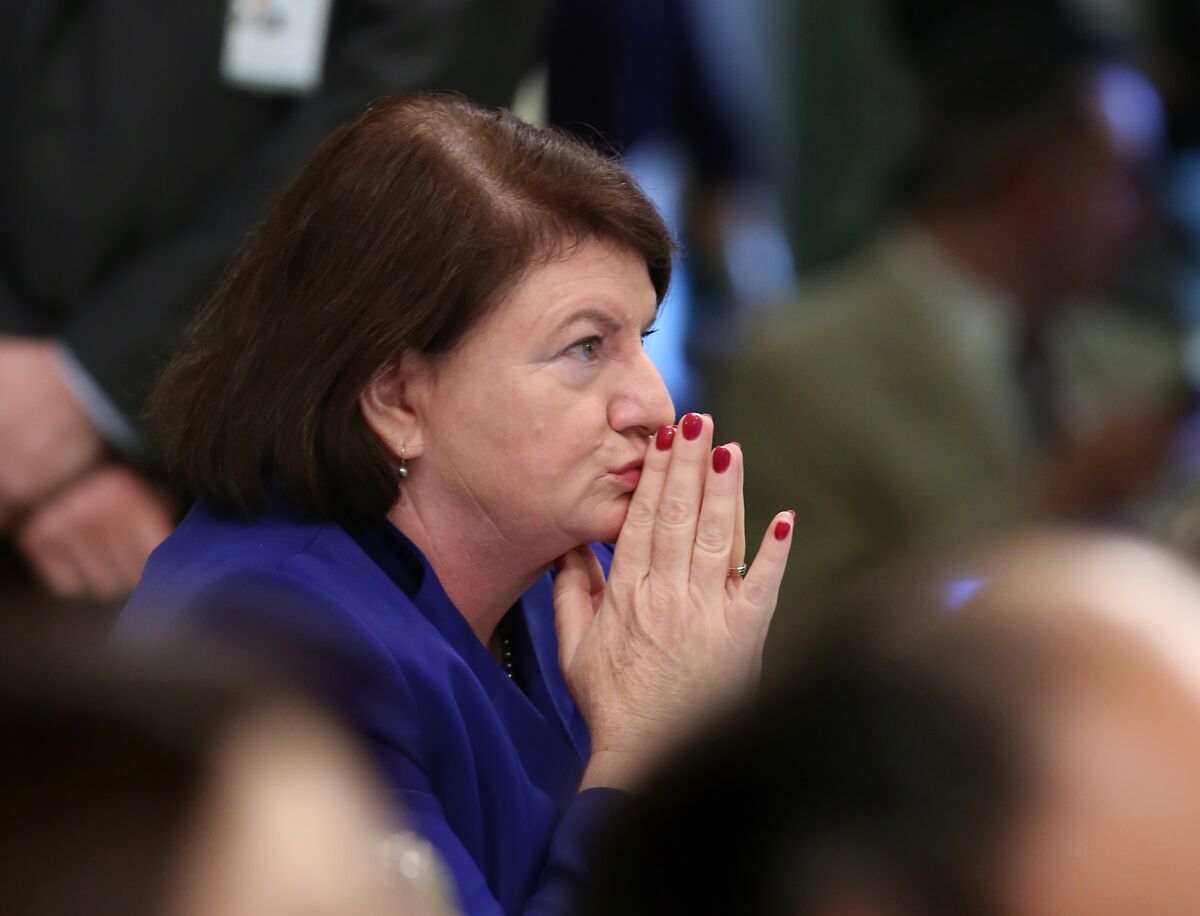 Toni Atkins sits among lawmakers, listening with her hands tented.