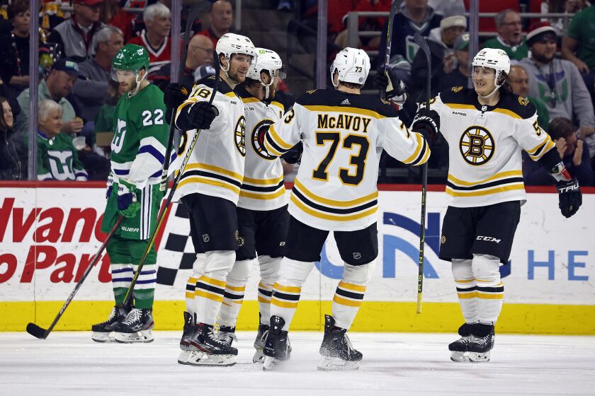 Boston Bruins Pavel Zacha, Charlie McAvoy (73) and Tyler Bertuzzi celebrate a goal with David Pastrnak, second left, as Carolina Hurricanes' Brett Pesce (22) skates nearby during the second period of an NHL hockey game in Raleigh, N.C., Sunday, March 26, 2023. (AP Photo/Karl B DeBlaker)