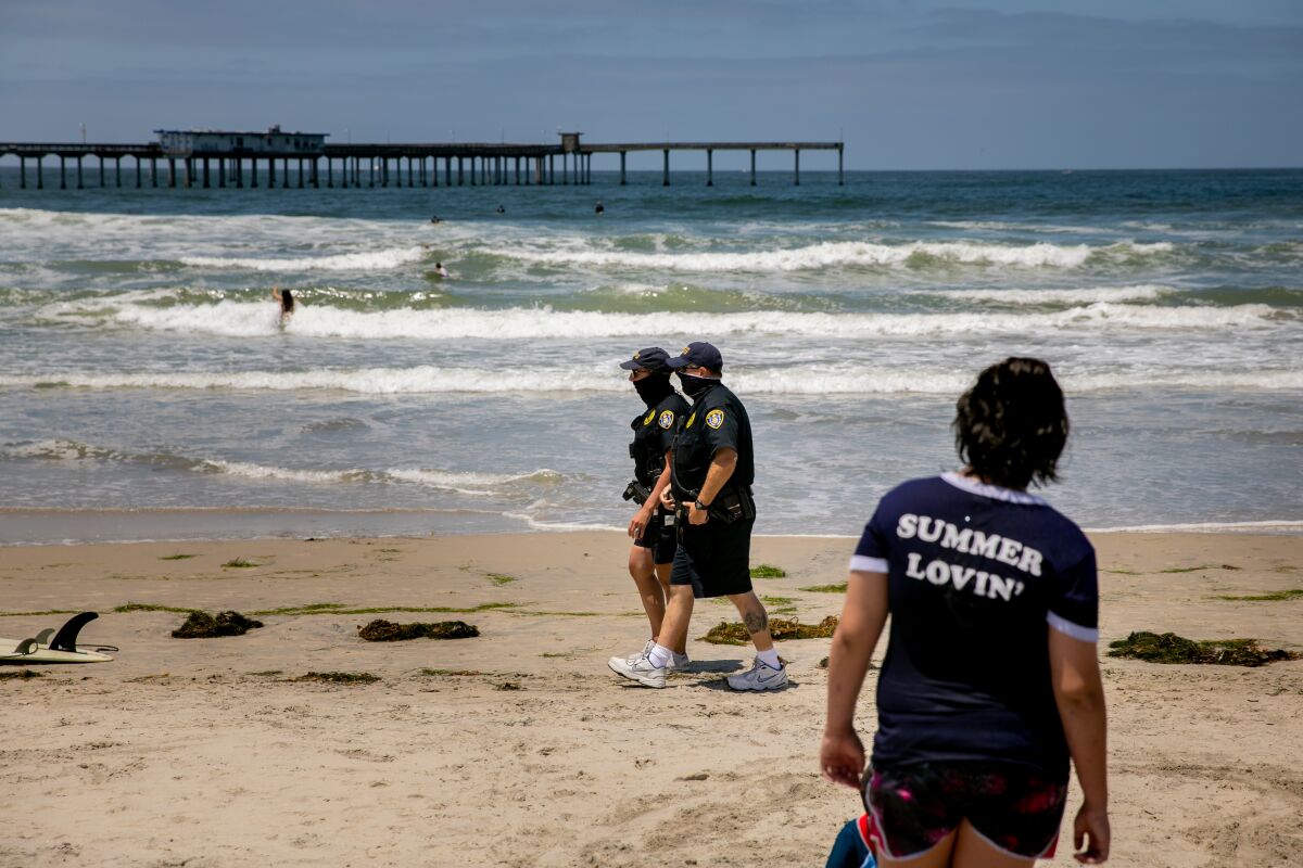 Two San Diego Police Department officers patrol along Ocean Beach ahead of Memorial Day Weekend on May 22, 2020 in San Diego, California.
