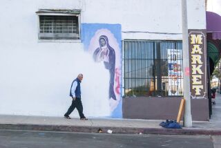 En esta fotografía de Oscar Rodriguez Zapata, un hombre camina al lado de un mural de la Virgen de Gualupe parcialmente cubierto con pintura en una pared en Los Ángeles, en 2018. (Oscar Rodriguez Zapata vía AP)