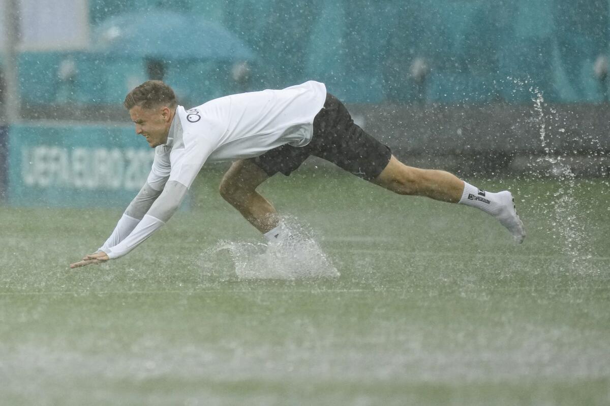 Austria's Christoph Baumgartner takes a dive on the pitch during a heavy rainfall before a training session at the National Arena stadium in Bucharest, Romania, Saturday, June 12, 2021, the day before their first match against North Macedonia. (AP Photo/Vadim Ghirda)
