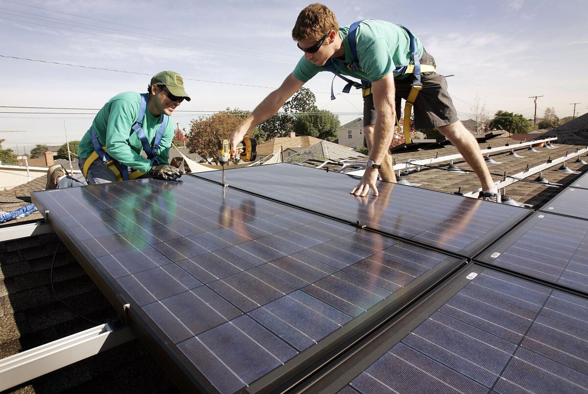SolarCity workers install solar modules on the roof of a Long Beach home. The company increased the size of its IPO but lowered the expected share price.