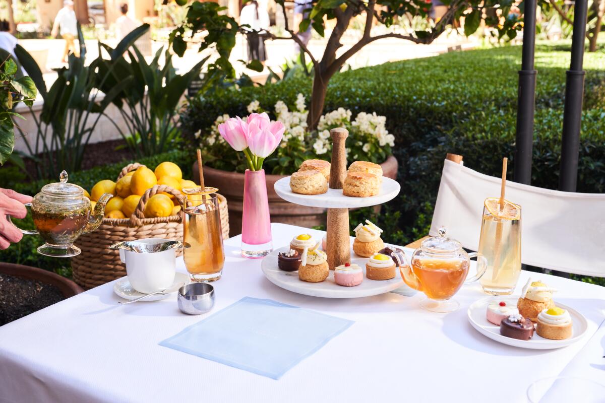 tiered pastry tray with tea sets on a table outside 