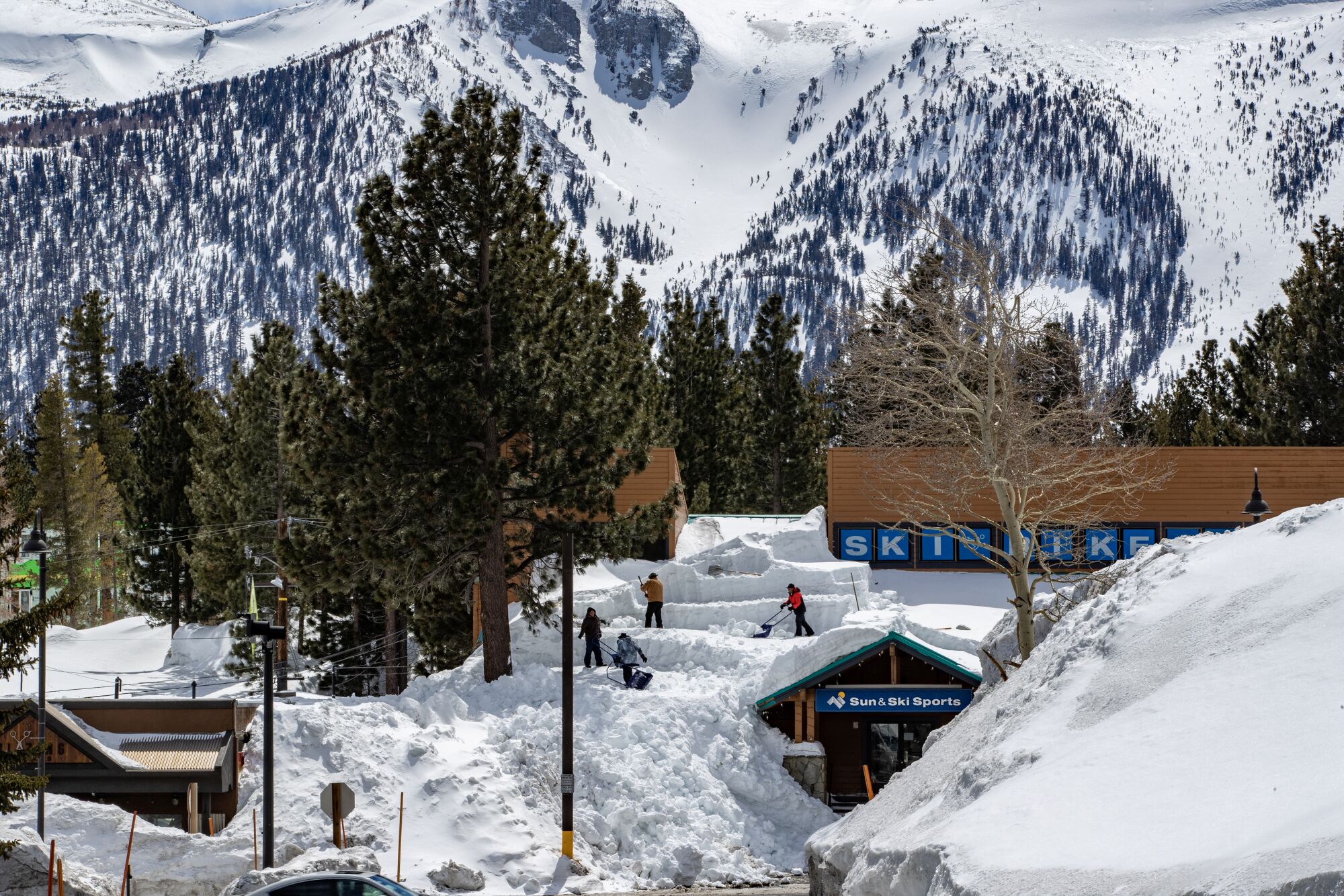 Workers remove mounds of snow on the roof of the Sun & Ski Sports retail shop