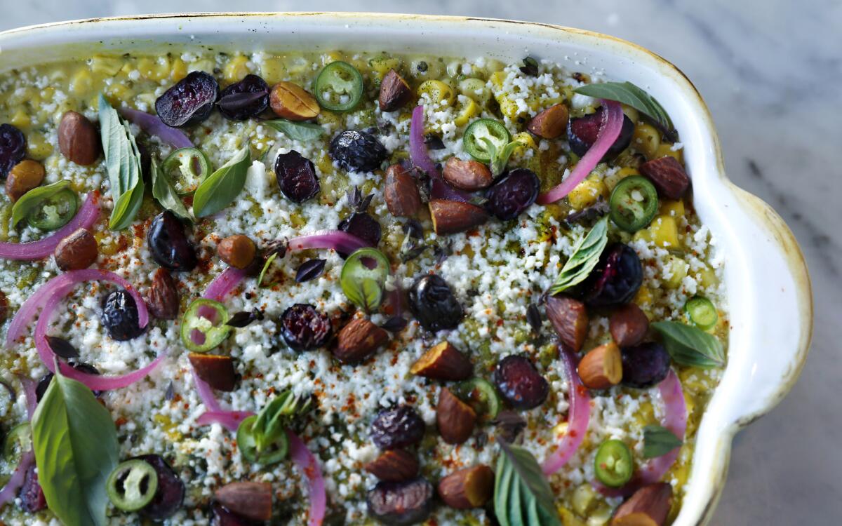 Esquites topped with pickled blueberries, vadouvan-spiced almonds, avocado-leaf powder, grated goat cheese and fresh herbs. 