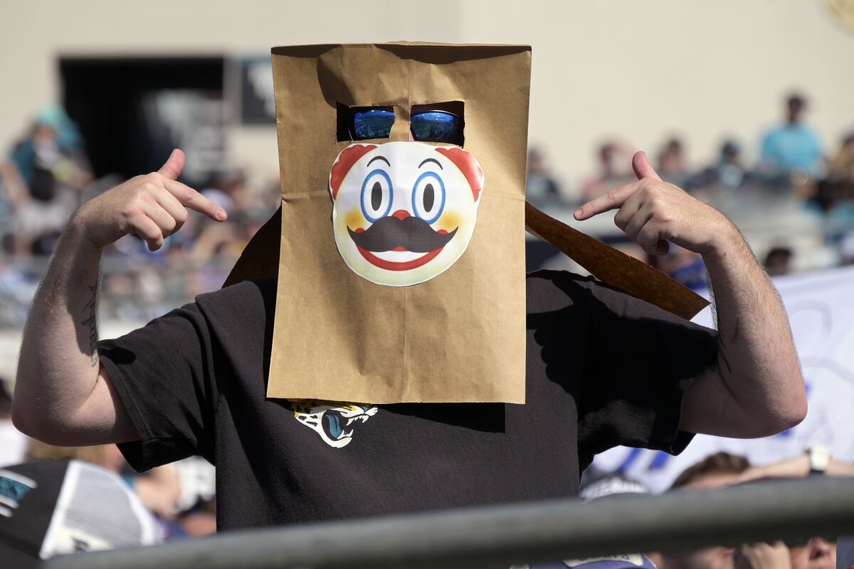 A fan with a bag over his head with a clown face watches the second half of an NFL football game between the Jacksonville Jaguars and the Indianapolis Colts, Sunday, Jan. 9, 2022, in Jacksonville, Fla. (AP Photo/Phelan M. Ebenhack)