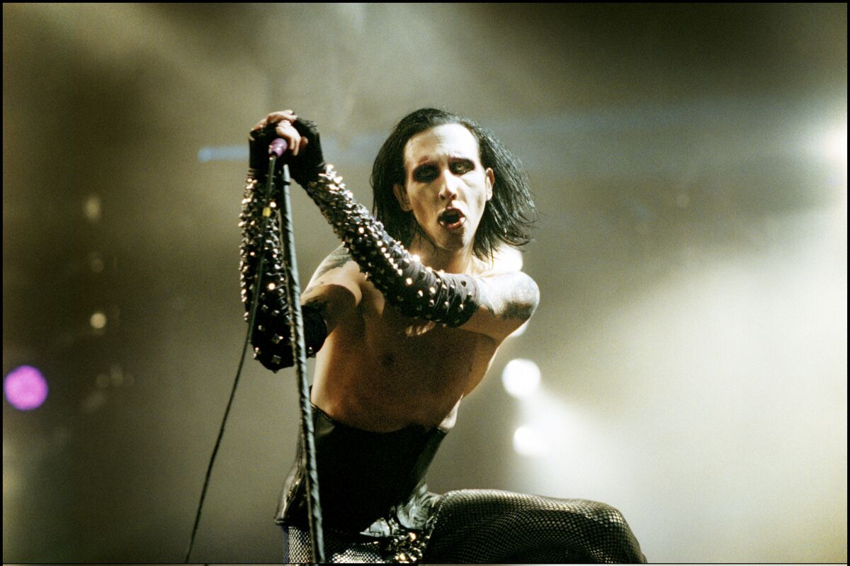 Marilyn Manson performing onstage, shirtless and with studded leather elbow-length gloves.