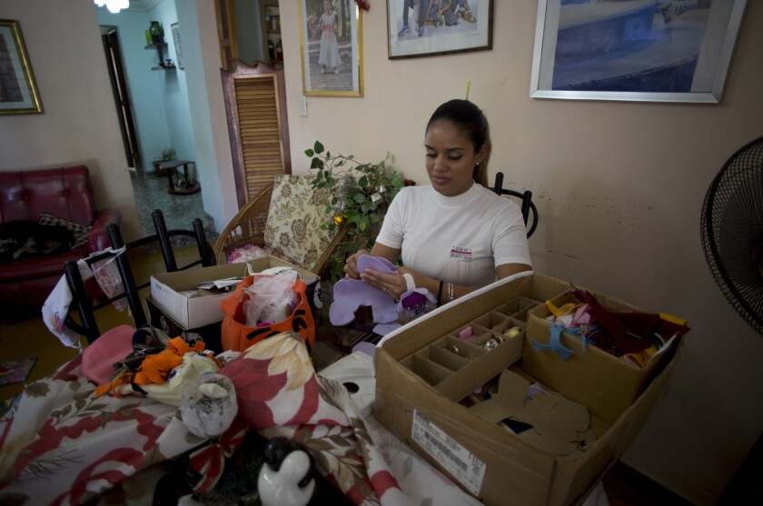Natalhie Fonseca makes soft toys for children that she sells under her brand "Carrete" in Havana, Cuba, Sunday, Dec. 26, 2021. The 32-year-old mother of two girls helps her husband run a cafeteria while she runs her business, an online store of children's products that she manufactures with hypoallergenic fillers. (AP Photo/Ismael Francisco)