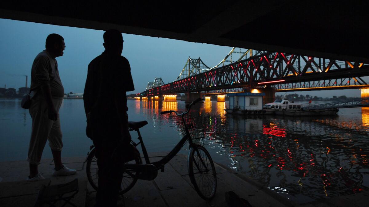 Two Chinese men chat near the China-North Korea Friendship Bridge between the North Korean town of Sinuiju (rear) and Dandong (foreground), in northeast China on Sunday.