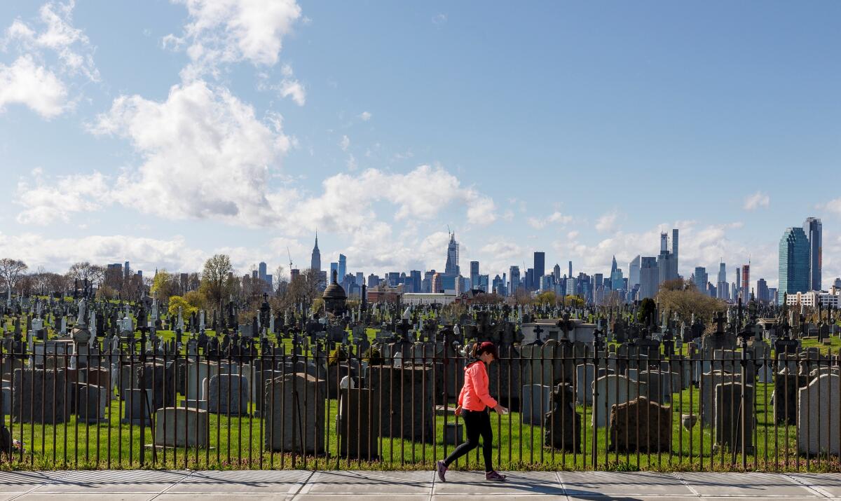 Una persona pasa por el cementerio Calvary en Queens con el horizonte de la ciudad al fondo en Nueva York, Nueva York, EFE/EPA/Justin Lane