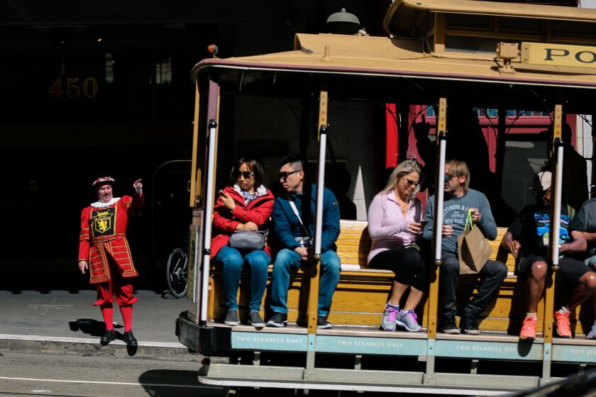 Sir Francis Drake hotel doorman Tom Sweeney greets a cable car as it rides past the hotel on Powell Street in San Francisco, California, on Thursday, April 27, 2017. (Photo by Gabrielle Lurie/San Francisco Chronicle via Getty Images)