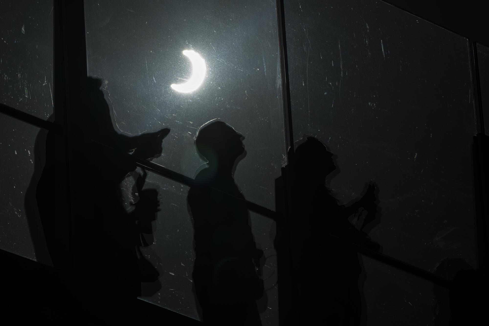 People watch a rare "ring of fire" solar eclipse in the dark.
