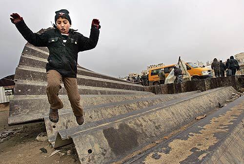 A Palestinian boy hops over the Gaza border. More than 500,000 Palestinians have crossed into Egypt through the Rafah post in the last week since a security breach of a border wall.