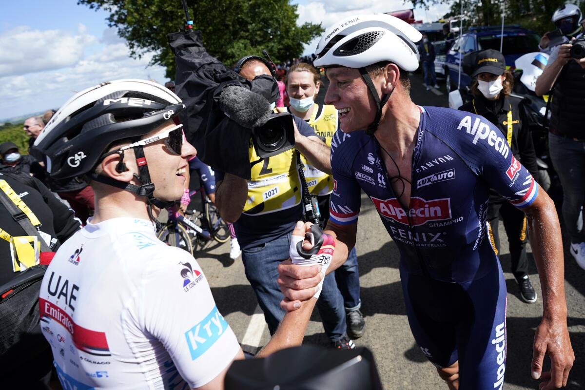 Tadej Pogacar grips Mathieu van der Poel's hand at the end of the second stage of the Tour de France.