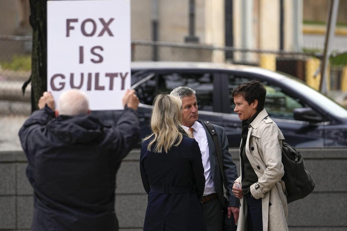 A protester holds a sign that says Fox is Guilty.