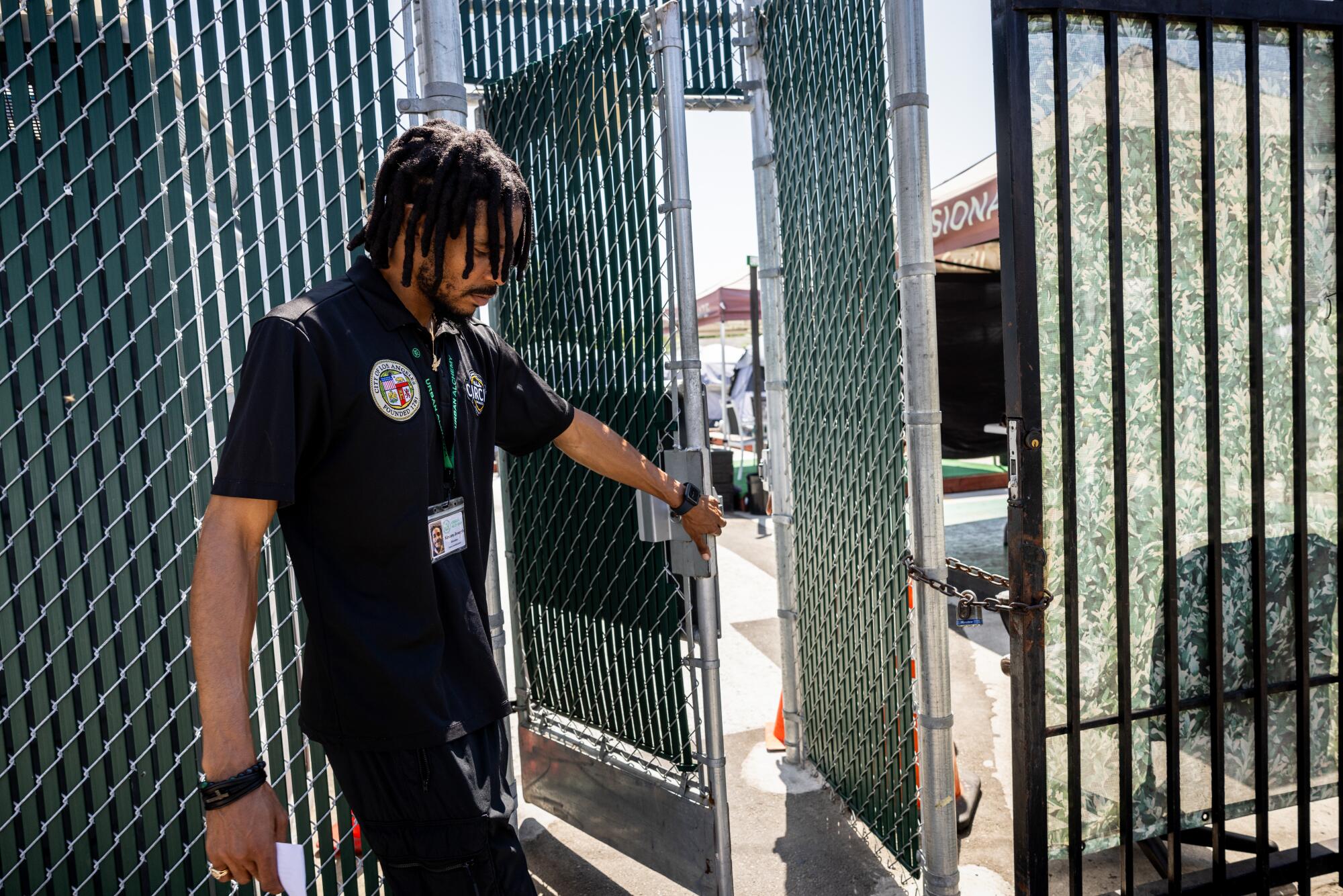 Kenon Joseph holds a security gate open at the Urban Alchemy homeless site