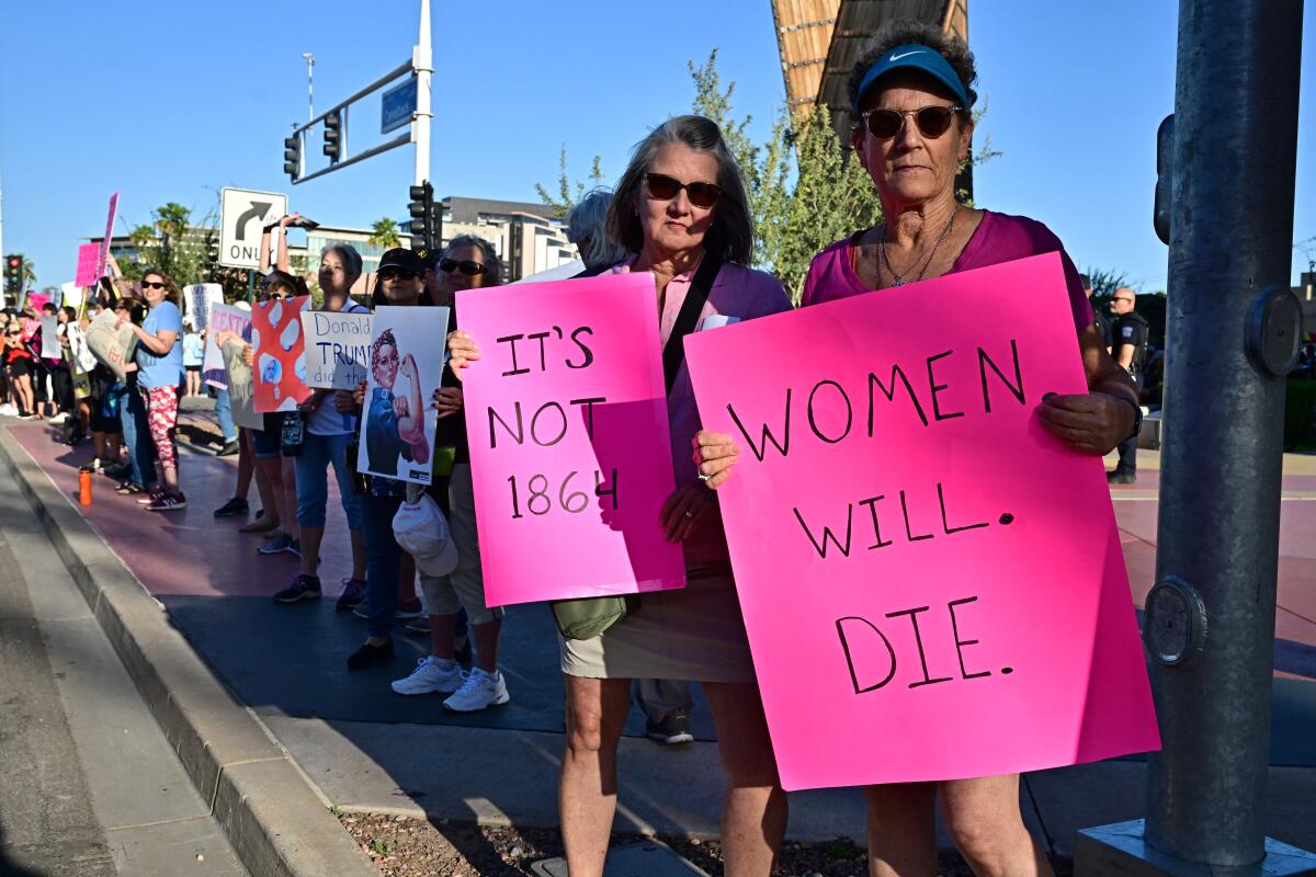 A line of protesters with signs that read "It's not 1864" and "Women will die." 