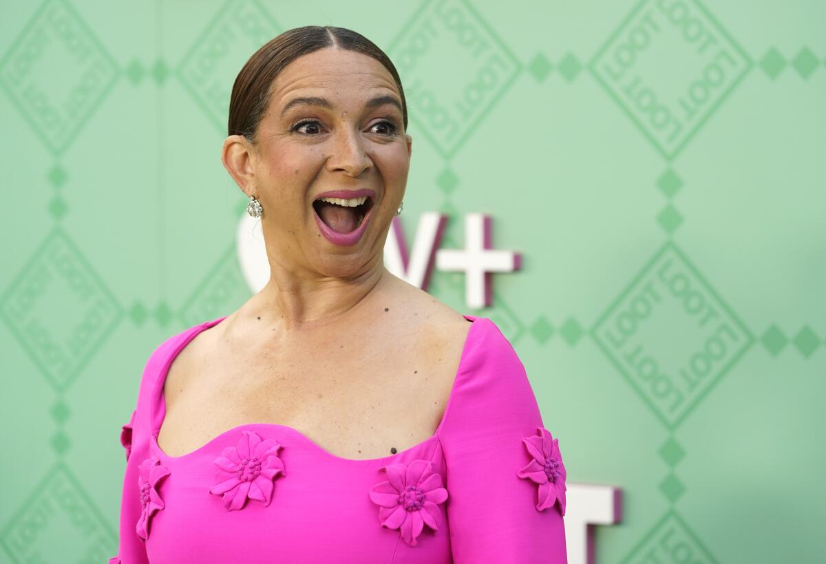 A woman in a pink gown opens her mouth while smiling