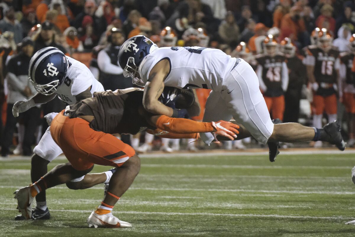 Toledo's Bryant Koback, right, is stopped by Bowling Green's Trent Simms as Toledo's Devin Maddox (8) tries to block during the first half of an NCAA college football game Wednesday, Nov. 10, 2021, in Bowling Green, Ohio. (J.D. Pooley/Sentinel-Tribune via AP)