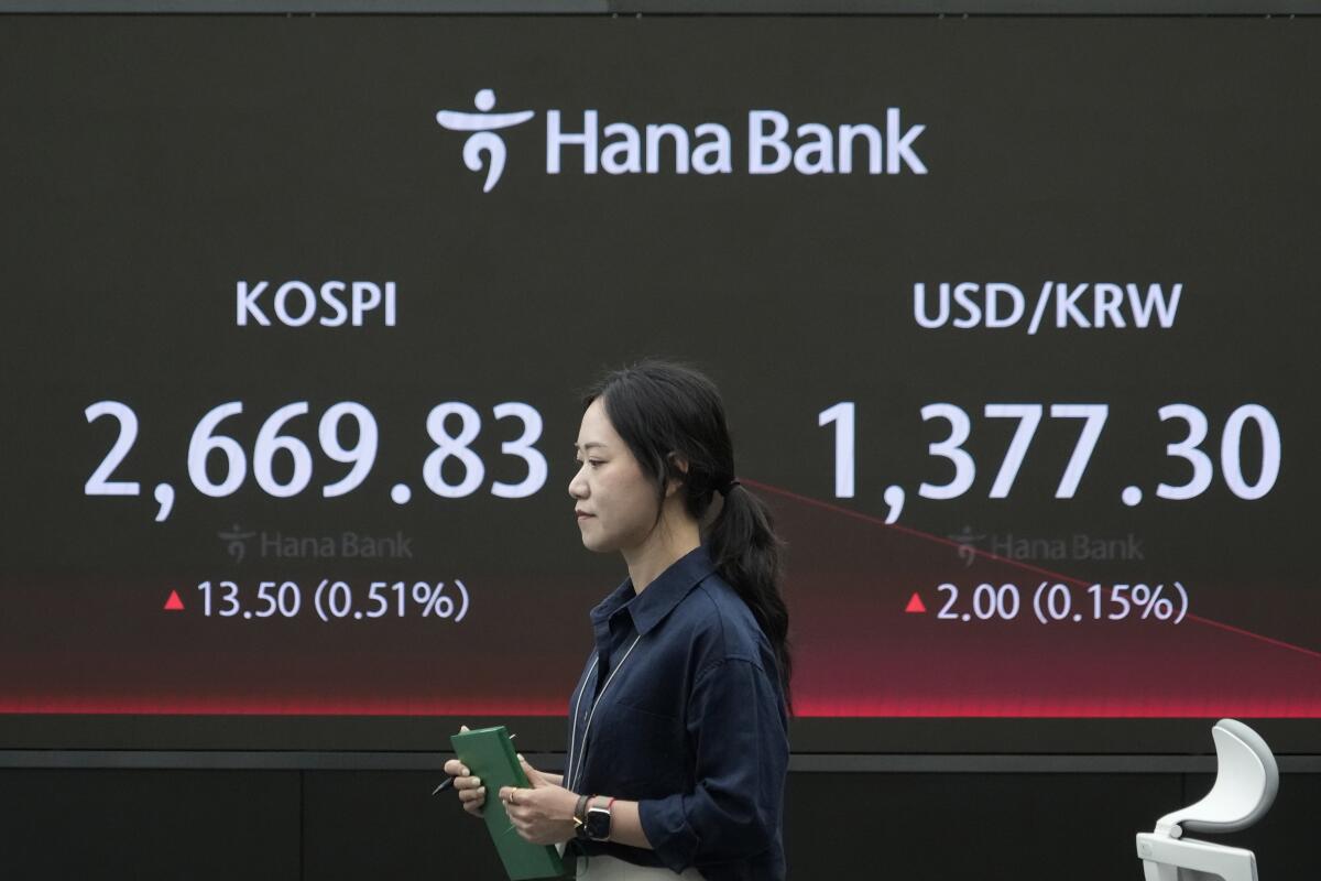 A currency trader passes by the screen showing the Korea Composite Stock Price Index 