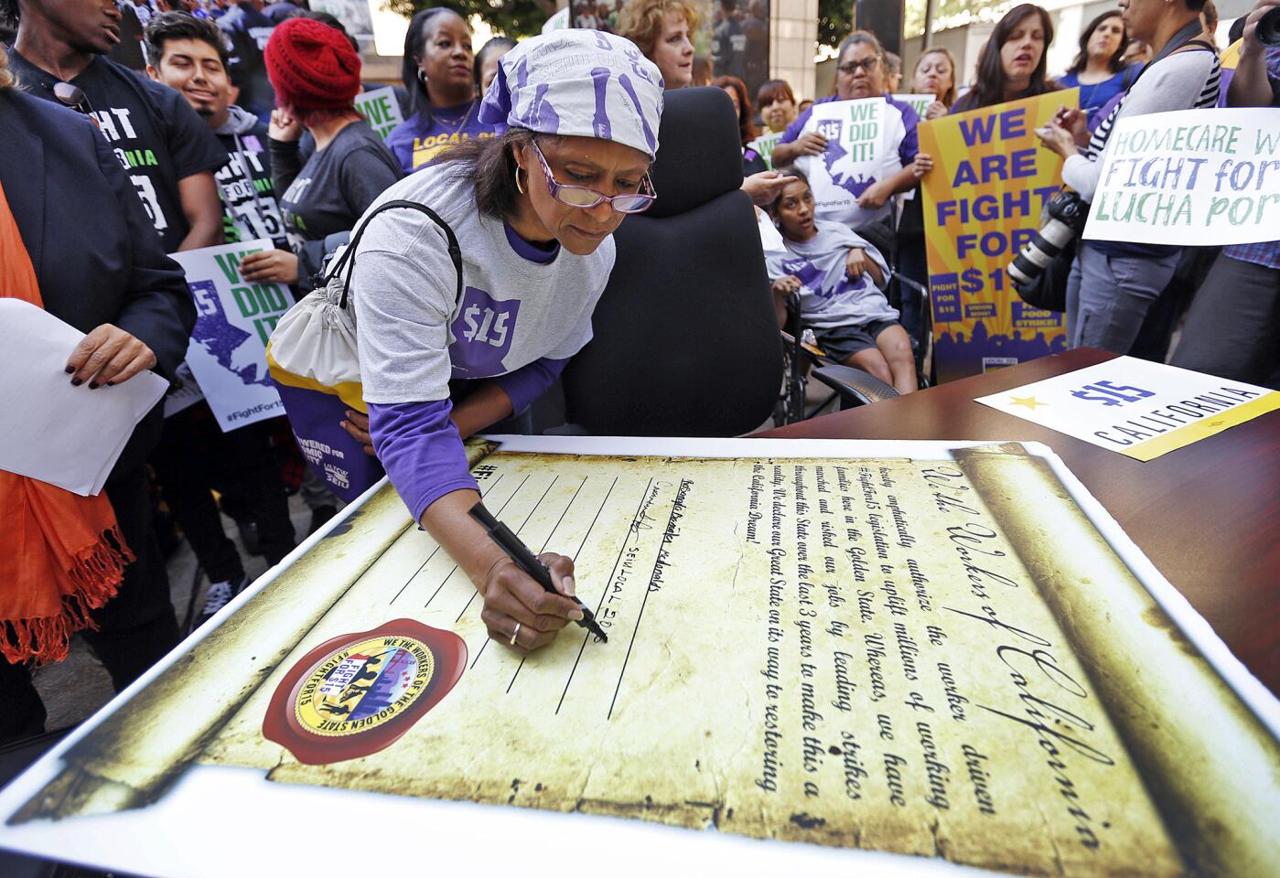 Cassandra Sanchez, a member of the union that represents long-term healthcare workers, signs a symbolic bill during a rally celebrating California's minimum wage hike.