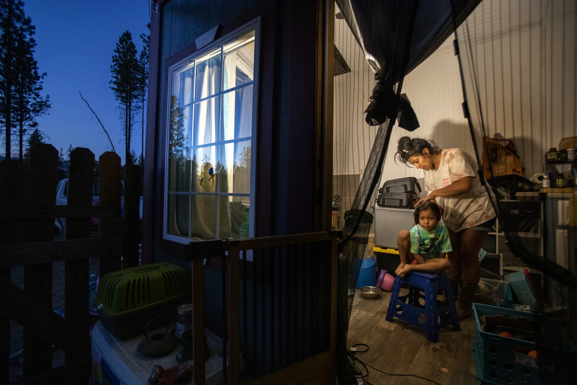 A woman brushes her daughter's hair at home.