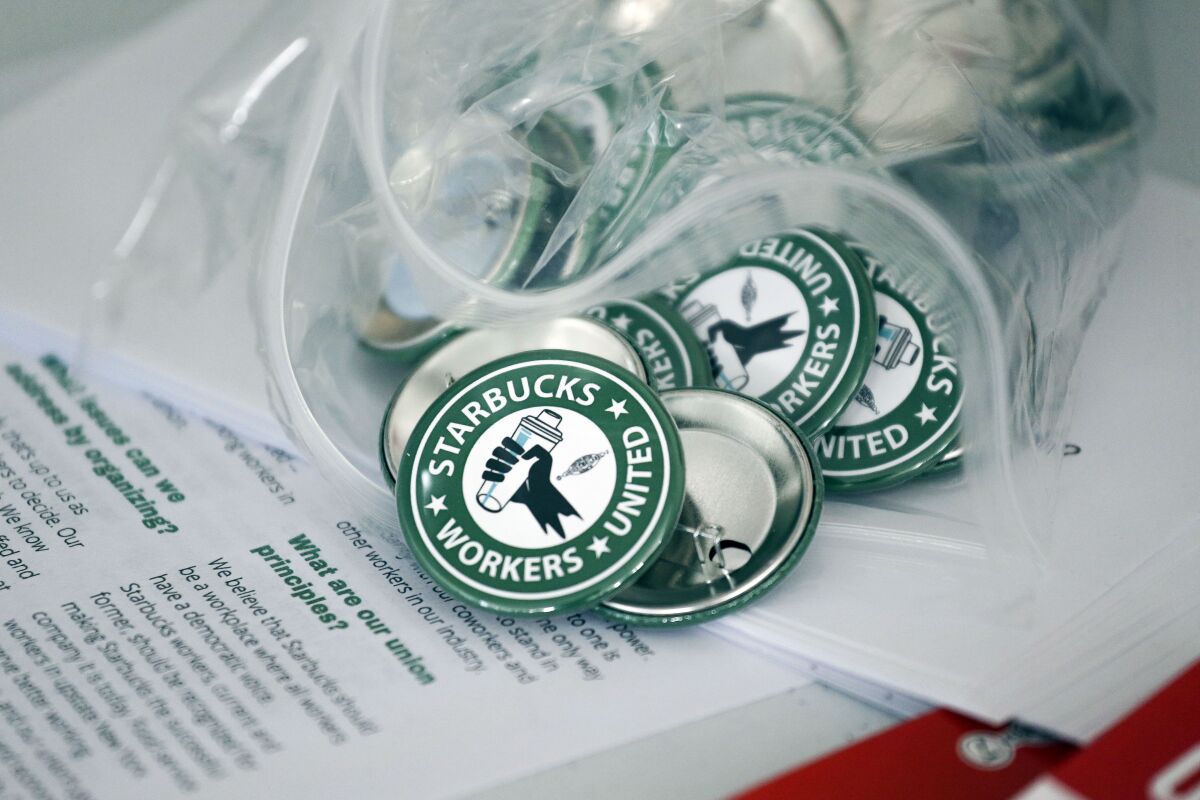 FILE — Pro-union pins sit on a table during a watch party for Starbucks' employees union election, Dec. 9, 2021, in Buffalo, N.Y. Starbucks says it will negotiate in good faith with workers who’ve agreed to unionize in Buffalo. In a bargain letter sent to all U.S. partners, Executive Vice President Rossann Williams said that the company hasn’t wanted unionization, but respects the legal process and wants to work with those in Buffalo who voted in favor of union representation. (AP Photo/Joshua Bessex, File)