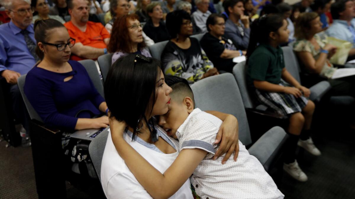Perla Esparza, left, holds her son Joshua Del Campo, 12, both of Los Angeles during the Los Angeles school board meeting.