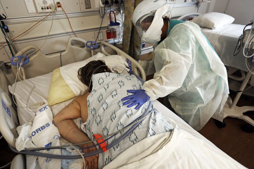 Los Angeles County, Sylmar, California-Jan. 12, 2020-At Olive View-UCLA Medical Center, a COVID-19 patient is placed on her stomach to assist with breathing after her oxygen level dropped below 90. RN Susha Abraham takes care of the patient in one of the COVID-19 wings of the hospital. Olive View-UCLA Medical Center is one of the primary healthcare delivery systems in the north San Fernando Valley. (Carolyn Cole / Los Angeles Times)