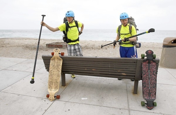 Cousins Kenton Durfee, left, and Mason Bennett gear up at Aliso Beach as they continue down the California coast on longboard skateboards to raise funds for Bridge of Love organization to benefit abandoned children in Romania.