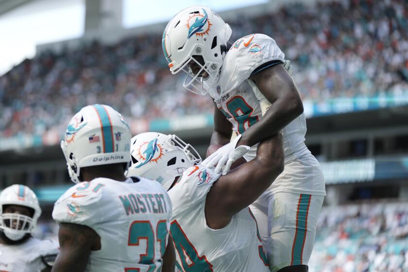 El defensive tackle Christian Wilkins (94), levanta a su compañero de los Dolphins de Miami De'Von Achane (28) después de que anotó un touchdown en la segunda mitad del partido ante los Broncos de Denver, el domingo 24 de septiembre de 2023, en Miami Gardens, Florida. (AP Foto/Rebecca Blackwell)