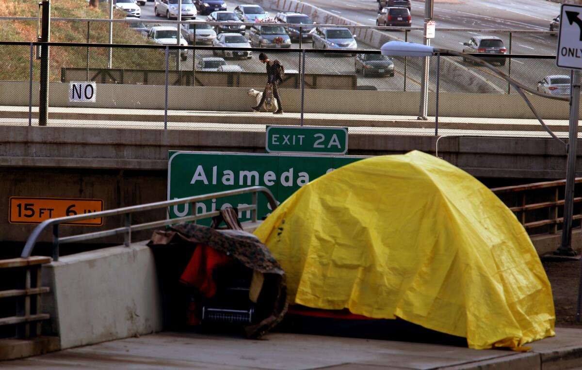 A homeless person takes shelter in a tent along Aliso Street above the 101 Freeway in downtown Los Angeles.