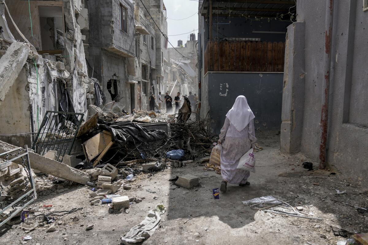 Women walk by rubble after an Israeli military raid.