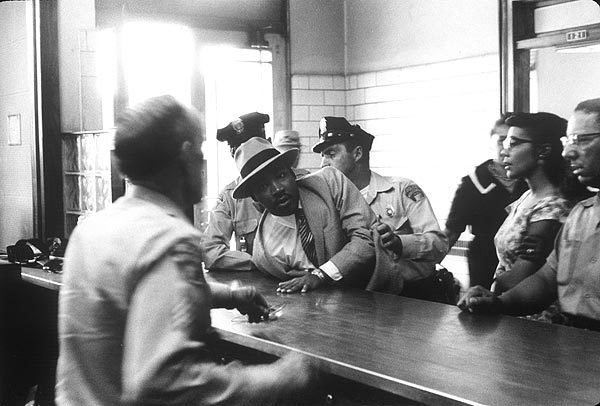 Montgomery, Ala., 1958: The Rev. Martin Luther King Jr. is sprawled across the booking desk at a police station as his stunned wife, Coretta, looks on. He was arrested for loitering at the Montgomery Courthouse and released when his identity became known to the police.